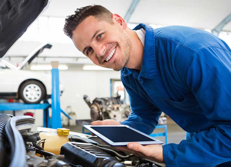 Dedicated service expert smiling over hood of car